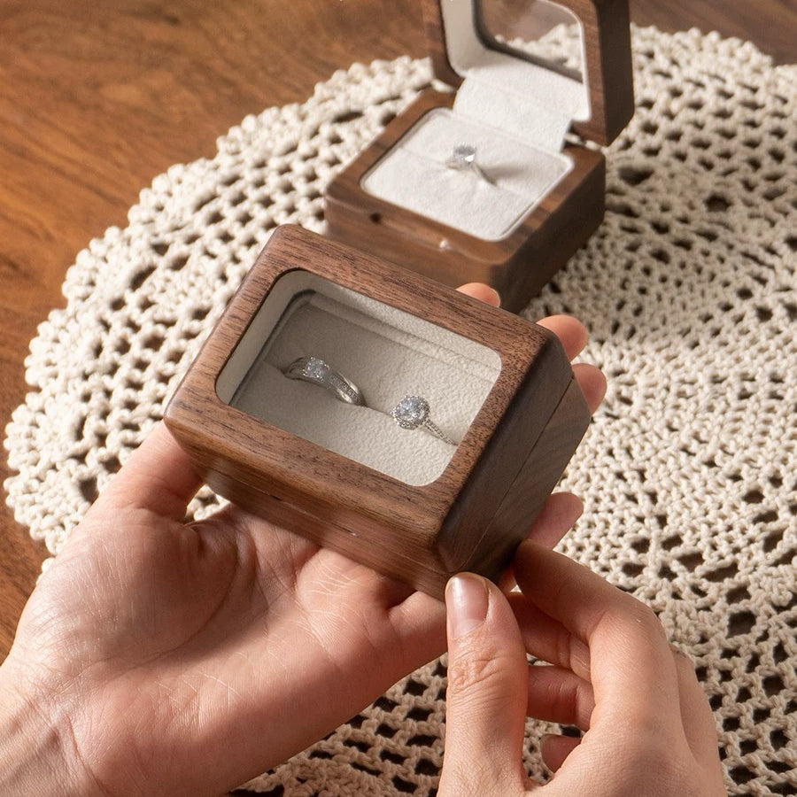 Open wooden ring box displaying a single ring
